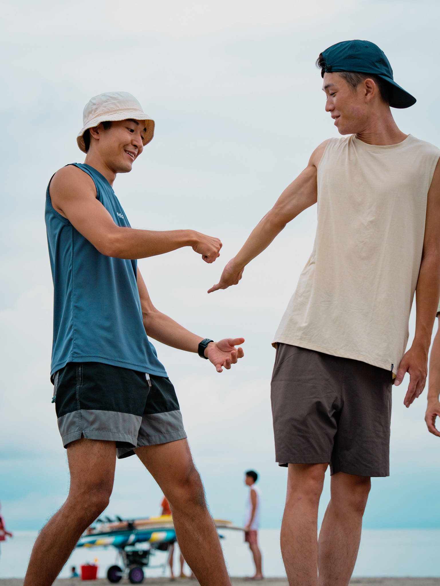 Hiroshi coaching a client through a mobility movement on the beach